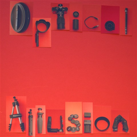 The words "Optical Allusion" formed by taking photographs of camera equipment arranged in the shapes of letters, each of them are set against a primary red background card.